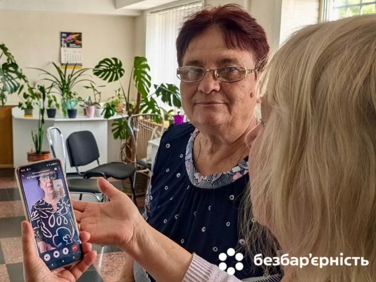 Жінка робить знімок іншої жінки, тримаючи телефон у руках